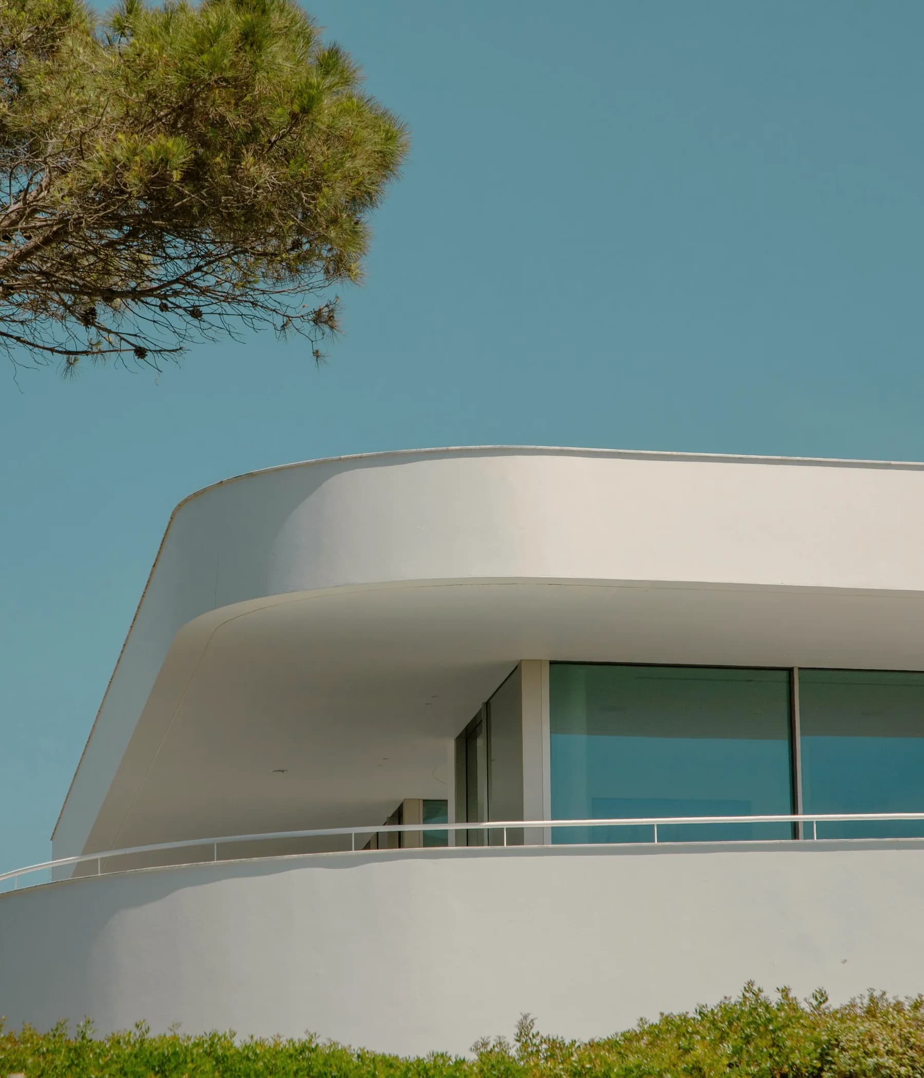 Moradia contemporânea branca com linhas curvas e jardim